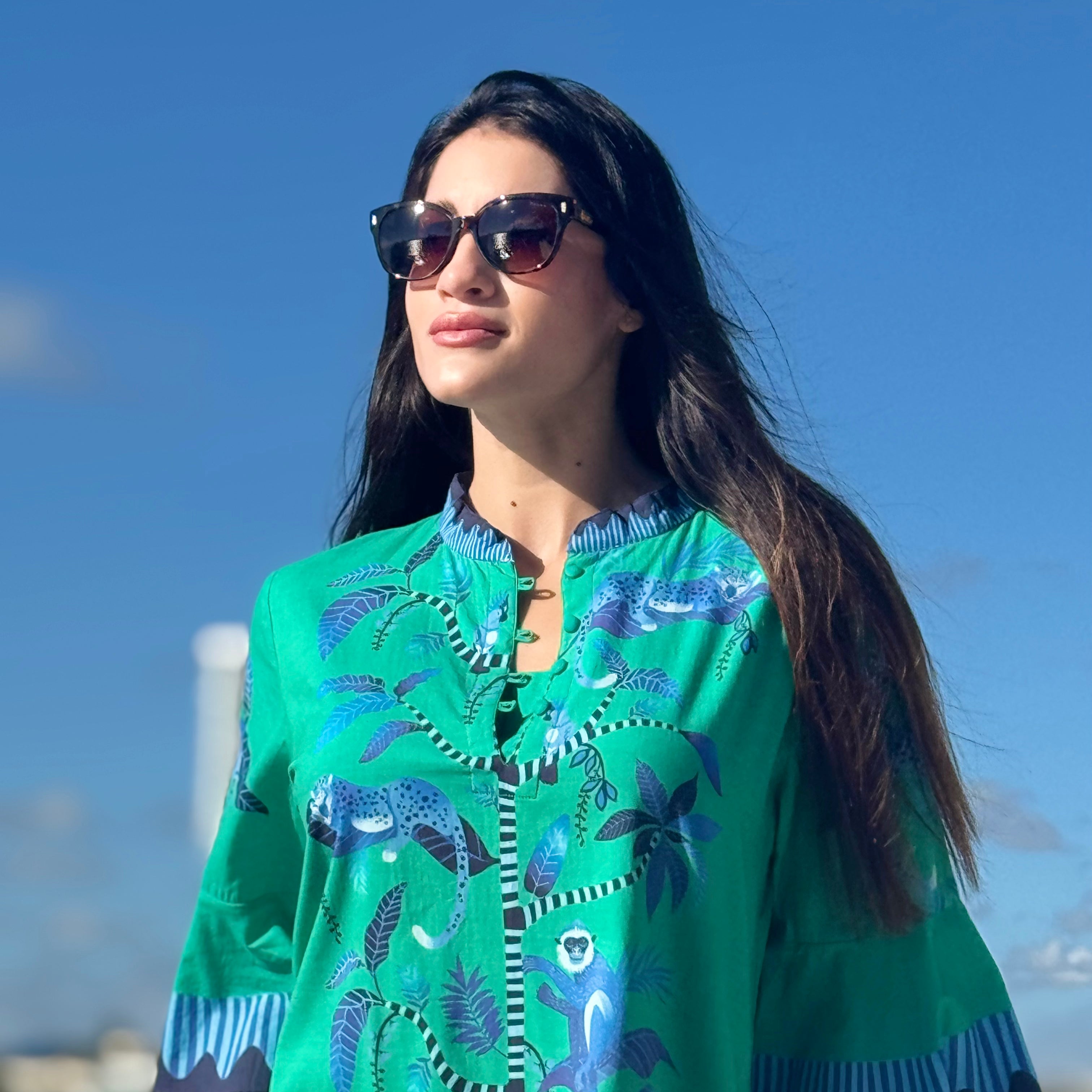 Woman wearing a green embroidered dress with a blue sky background